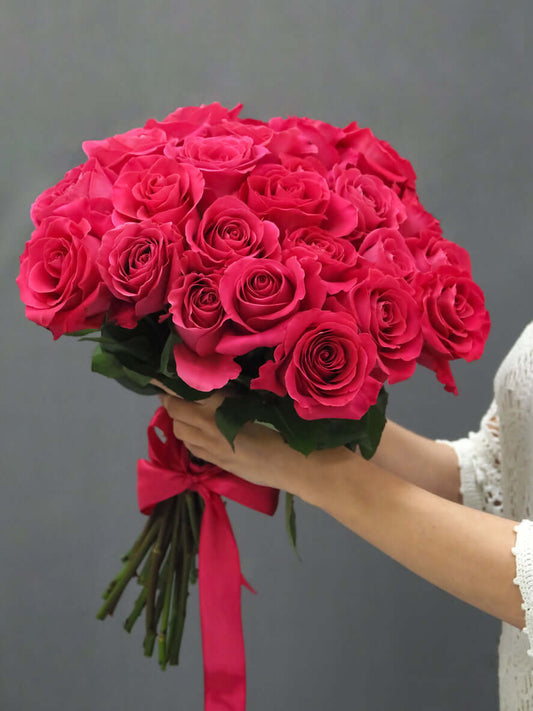 Rosenstrauß "Pink Floyd" mit leuchtend pinken Rosen, kunstvoll gebunden und präsentiert von einer Hand.